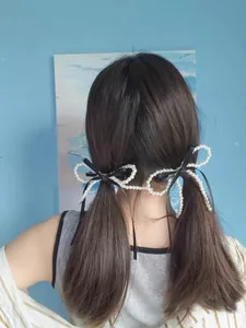 Detail view of pearl bow hair clips set worn on pigtails for a sweet elegant hairstyle