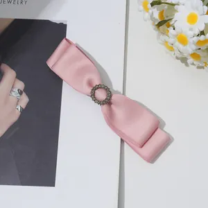 Detail einer rosa Satin-Doppelschleife-Haarspange mit Vintage-Strassstein auf Magazin-Hintergrund