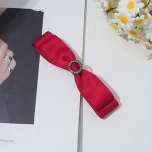 Detailaufnahme der roten Satin-Doppelschleifen-Haarklammer mit glitzerndem Strass-Dekor
