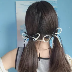 Elegant pair of pearl bow hair clips for women with black silk ribbons in a half-up hairstyle