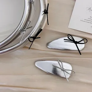 Detail showing silver teardrop hair clips with black and silver bows on silk