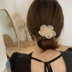 Elegant off-white mesh flower hair tie with pearl center on low bun hairstyle