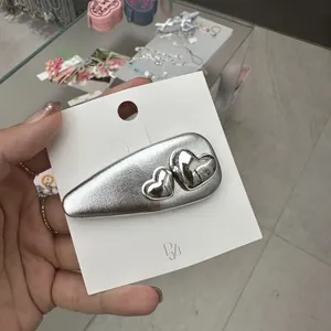 Pince à cheveux BB argentée avec accents de cœur métallique sur carte blanche