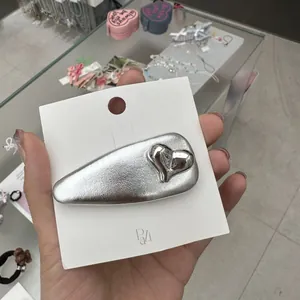 Barrette argentée en forme de goutte avec cœur brillant sur carte blanche