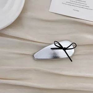 Detail of silver drop hair clip with black ribbon bow on vintage paper background