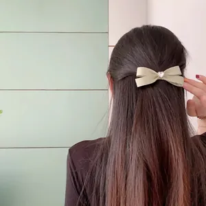 Elegant light green satin bow hair clip with pink heart gemstone worn on model's hair