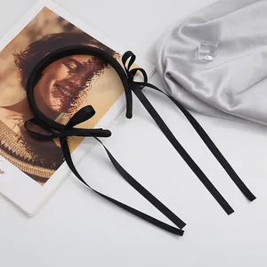 Elegant black satin ribbon bow headband with long streamers on a stylish silver background