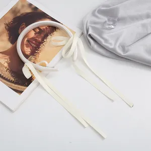 Detail of cream satin headband with elegant long flowing ribbons in a flat lay setup