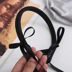 Elegant black satin headband with long ribbon bow and handmade label detail