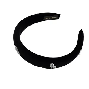 Padded black velvet headband with elegant pearl bow decorations in a minimalist style