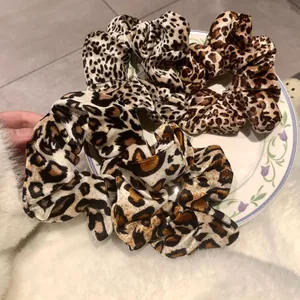 Trois chouchous motif léopard différents présentés sur une assiette fleurie en céramique