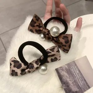 Set of two leopard print bow scrunchies featuring large white pearls on soft faux fur
