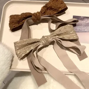 Elegant vintage bow hair clips with long silk ribbons and sequins in a cream tray