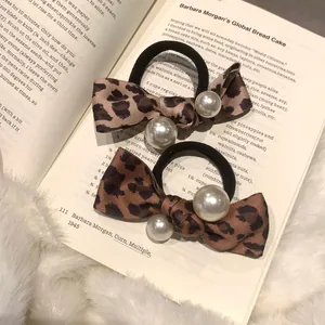 Vintage leopard bow hair scrunchies with white pearls set on aesthetic book background