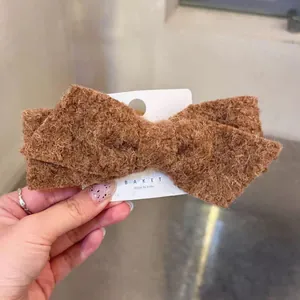 Brown plush bow hair clip with fuzzy wool texture on display card for autumn and winter
