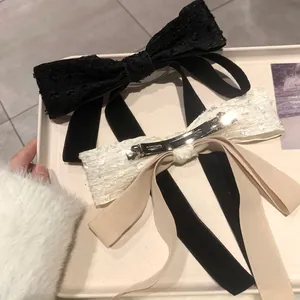 Close-up of black and white lace bow hair clips with long ribbons and metal spring clips