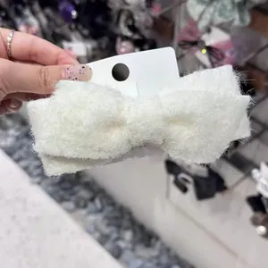 Elegant white wool bow hair clip accessory for women shown on product display card