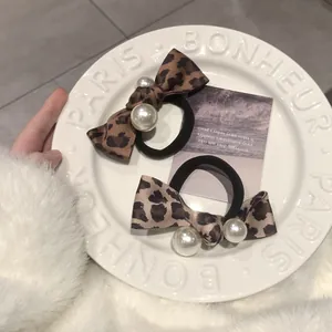 Close-up of leopard print bow hair ties with faux pearls on a white porcelain plate