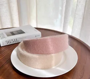 Detailed texture of plush wide headbands in soft pink and beige wool-like material