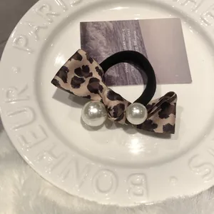 Vintage leopard print bow hair tie with pearl accents on a white decorative tray