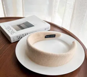 Detail of cream plush headband featuring a soft wool-like texture and Hand Made label