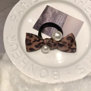 Detail of leopard print bow hair tie with elegant white faux pearls on ceramic tray