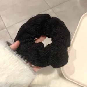 Detailed close-up of a black chunky knit hair scrunchie showing soft woolen texture