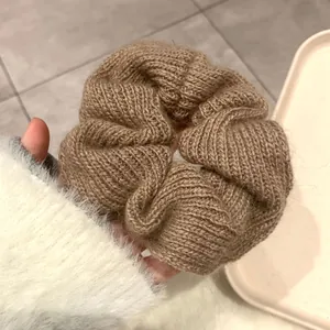 Close-up of a coffee brown chunky knit scrunchie with soft wool texture and braided design