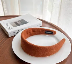 Close-up of caramel wool headband with handmade label on ceramic plate background