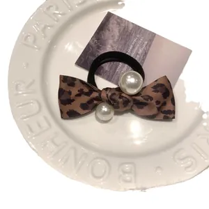Vintage leopard bow hair tie with pearls and elastic band on white ceramic tray
