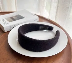 Detail of a handmade black wool felt headband on a white plate with soft lighting
