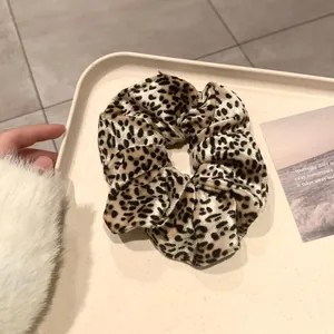 Détail d'un chouchou imprimé léopard en velours doux sur un plateau beige
