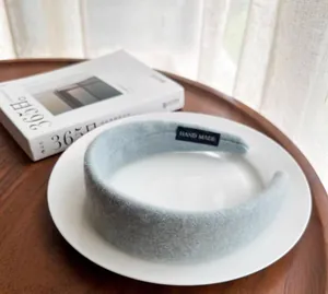 Close-up of a plush light blue wool headband with Hand Made label on a ceramic plate