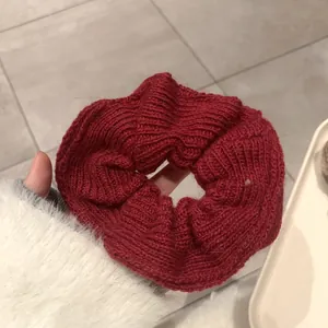 Detail shot of the deep red handmade knitted scrunchie showing thick wool texture