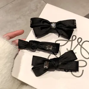 Dreiteiliges Set schwarze Satin-Haarspangen mit funkelnden Kristallen auf Displaykarte