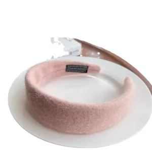 Handmade wide pink faux fur headband with soft wool texture for women shown on a white tray