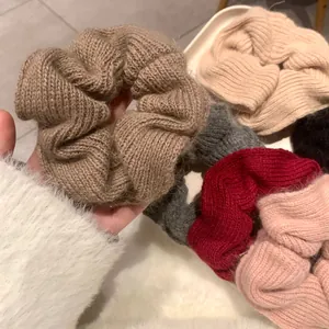 Handmade knitted scrunchies in various autumn colors held by a hand on a soft background