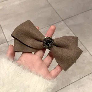 Close-up of brown wool bow hair clip with vintage jewel and sparkling crystal details