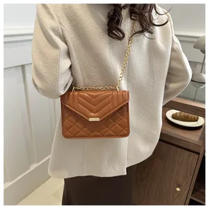 Side view of a quilted brown faux leather crossbody bag with golden chain strap and chic chevron flap