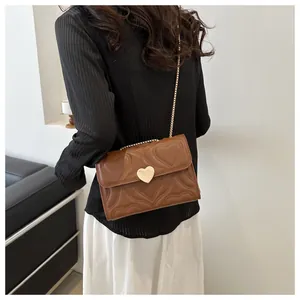 Detail showing brown heart-quilted texture with golden heart-shaped metal clasp buckle