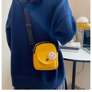 Gros plan sur le mini sac bandoulière en toile jaune vif avec badge lapin et sangle réglable