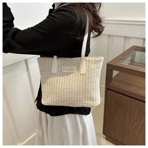 Detail of woven straw tote bag with leather FASHION & BAGS patch on model shoulder