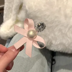 Handmade pink ribbon bow hair clip featuring an elegant pearl and sparkling crystal clusters