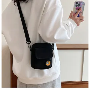 Detail of black canvas crossbody bag with orange patch worn by a model in casual style