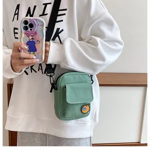 Detail of mint green canvas crossbody bag featuring a cartoon fruit patch and front pocket