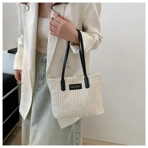 Detail of the straw tote bag showing clear woven texture and fashion letter label