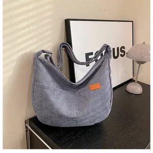 Detailed texture of light blue-grey corduroy crescent bag with orange sport label