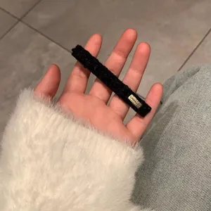 Cute black fuzzy hair clip with gold Lovedays metal plate held in hand for women