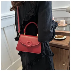 Burgundy faux leather crossbody bag styled with black dress in a cozy cafe setting