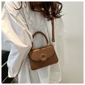Detail of a brown vintage mini square bag with a round buckle and top handle straps